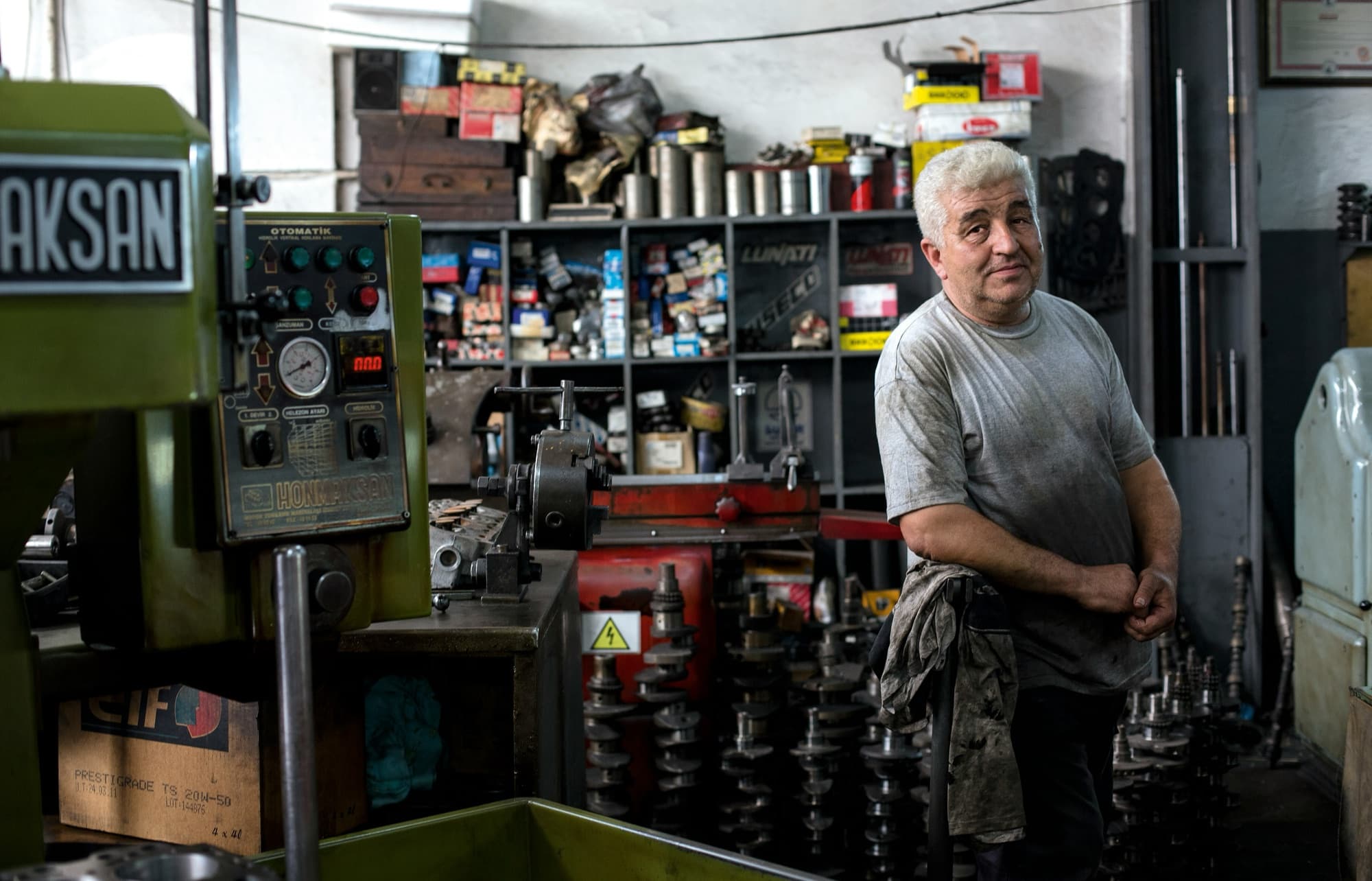 A machinist standing among the lathes, parts, and shelves of a small machine shop