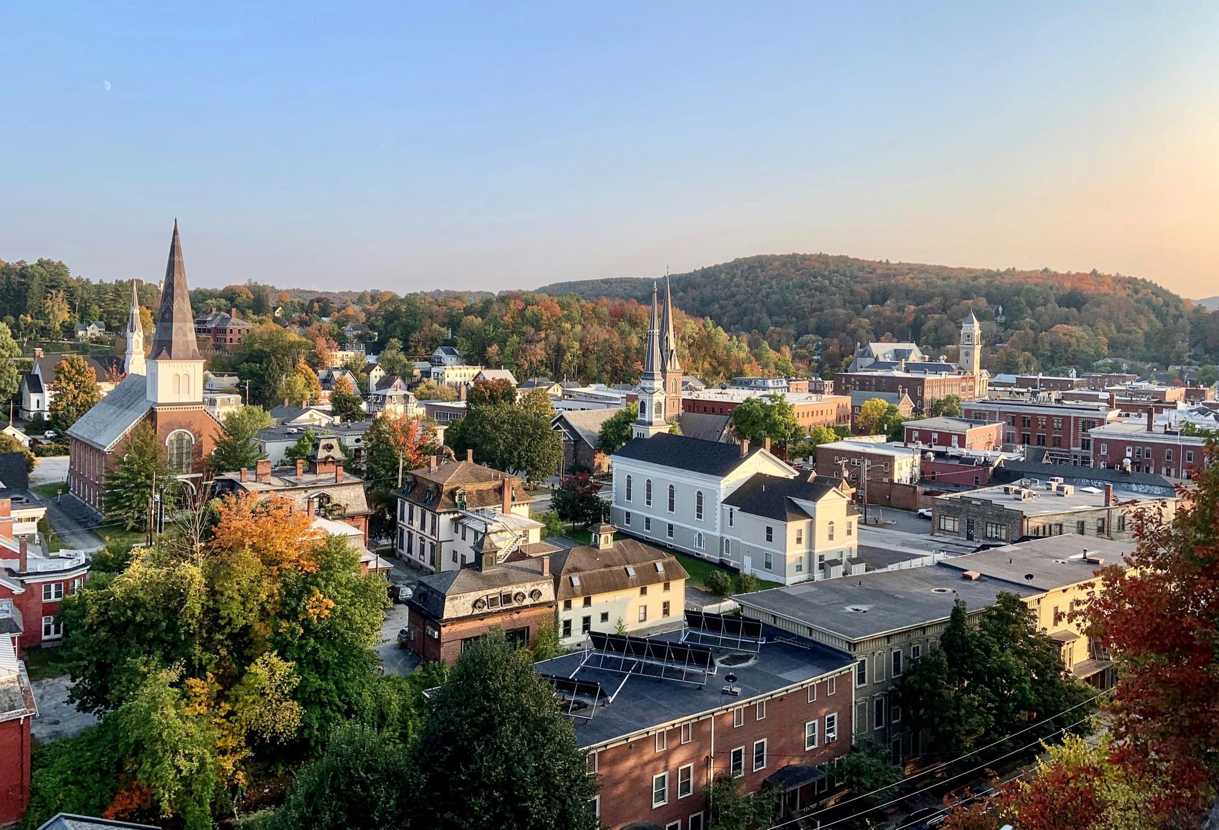 Downtown Montpelier from above in early autumn, church steeples and brick buildings against wooded hills